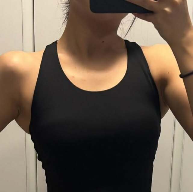 검은색 민소매 상의를 입은 사람이 거울 앞에서 상반신을 촬영한 사진