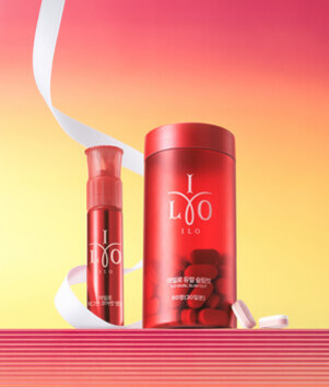 분홍색과 주황색 그라데이션 배경 앞에 빨간색 원통형 용기와 작은 펌프 용기, 그리고 알약이 놓여 있다. 용기에는 'ILO'라는 로고가 적혀 있다.