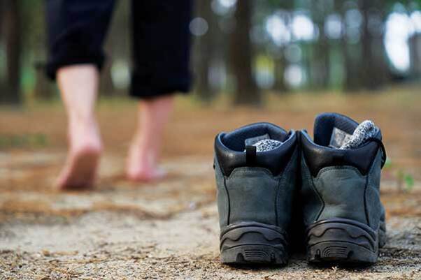 흙바닥에 신발 한 켤레가 놓여 있고, 맨발의 사람이 멀어져 가고 있다.