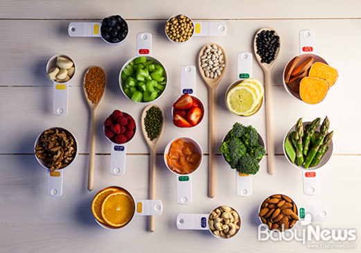 여러 가지 신선한 과일, 채소, 견과류 등이 계량스푼과 컵에 담겨 깔끔하게 배열되어 있는 사진