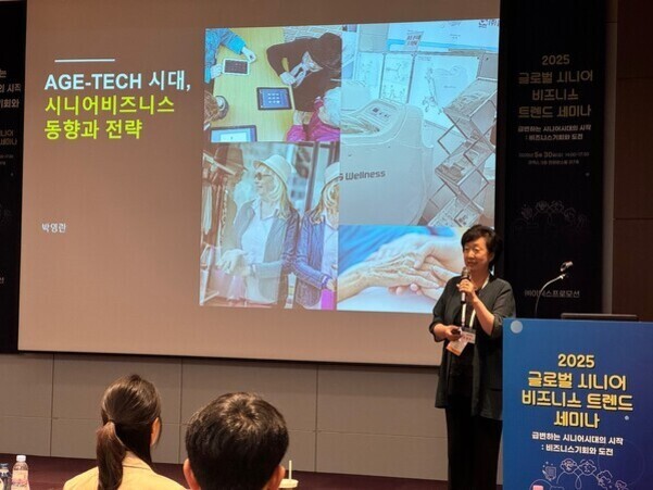 여성 발표자가 'AGE-TECH 시대, 시니어비즈니스 동향과 전략'이라는 제목의 프레젠테이션을 진행하고 있으며, 스크린에는 노인 관련 이미지와 텍스트가 표시되어 있다. 관객들이 발표를 듣고 있다.