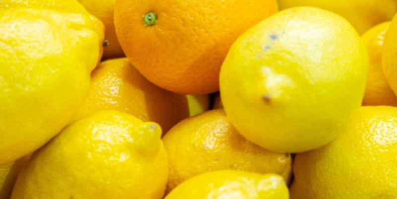 여러 개의 레몬과 한 개의 오렌지가 함께 쌓여 있는 모습