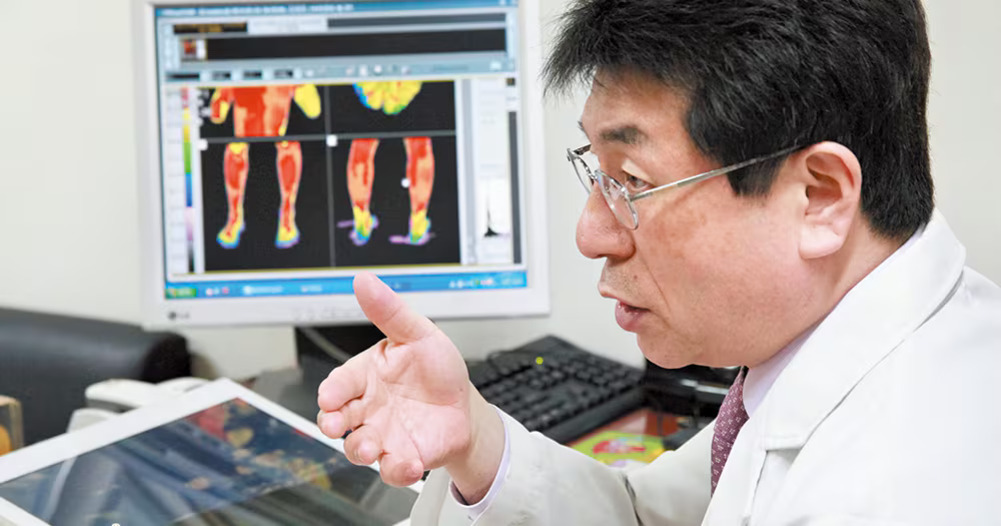 의사가 컴퓨터 모니터에 표시된 인체 열화상 이미지를 보며 설명하고 있다.