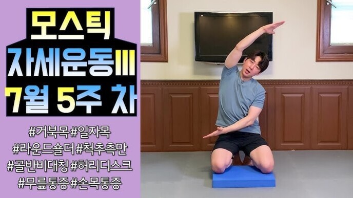 운동복을 입은 남성이 파란 매트 위에 무릎을 꿇고 앉아 왼팔을 머리 위로 들어 올려 옆구리를 스트레칭하는 자세를 취하고 있다. 왼쪽에는 '모스틱 자세운동 7월 5주 차'라는 큰 글씨와 해시태그들이 적혀 있다.
