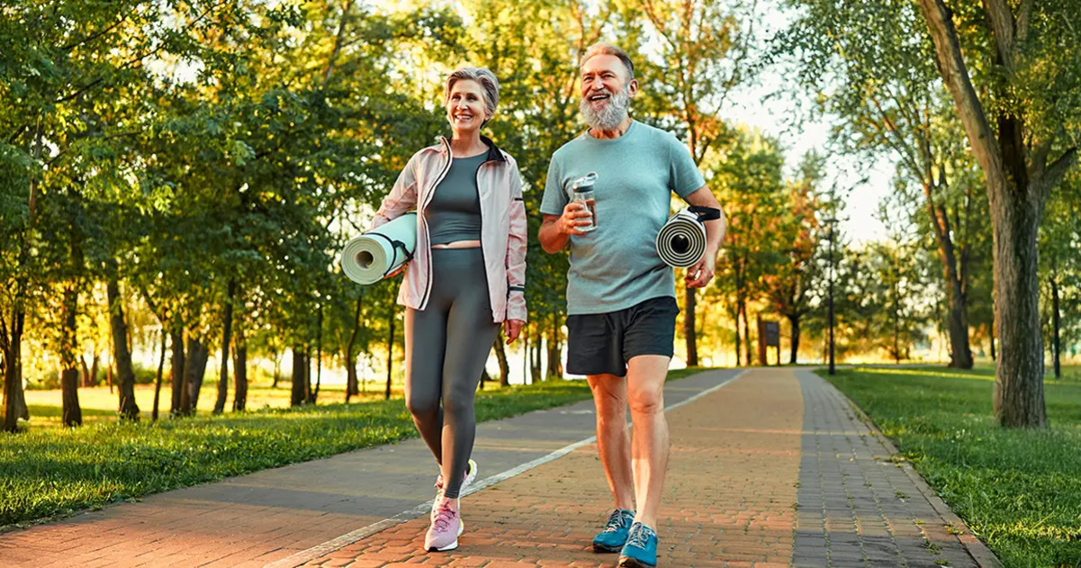 공원 산책로에서 요가 매트를 들고 걷는 중년 남성과 여성