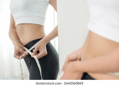 여성이 거울 앞에서 허리둘레를 줄자로 측정하고 있는 모습